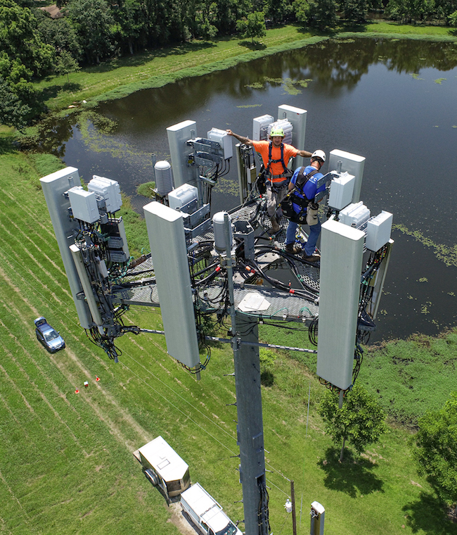 Tower climbers wave to the drone during an aerial tower inspection